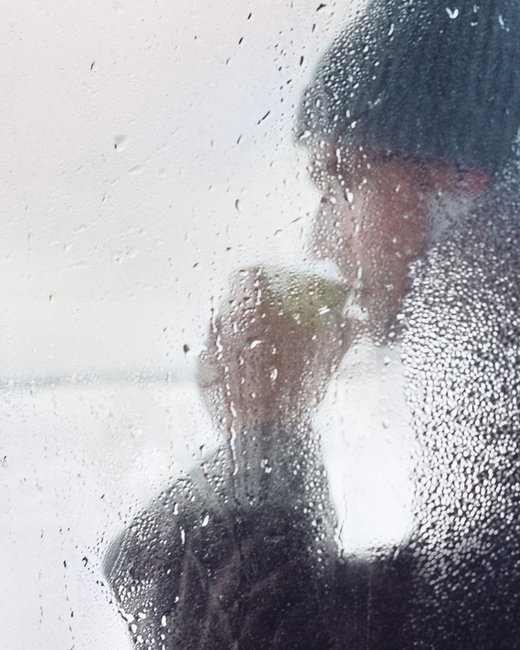 Finland winter, man drinking warm drink behind tarnished window